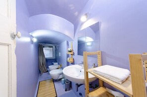 A compact bathroom with a white sink, a mirror, and a wooden shelf with a towel. - JOIVY Cosy Flat In The Centre (Genoa)