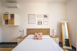 A neatly arranged bedroom with a large bed, two bedside tables with lamps, a wardrobe, and a mirror.