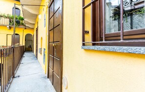 A narrow alleyway with yellow walls, a metal fence, and a door with a window. - JOIVY Studio Near Natural Museum (Milan)