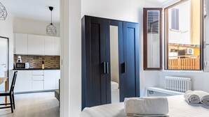 A modern bedroom with a large bed, a dark wardrobe, and a view of the outside. - JOIVY Cosy 1-Bed Flat In Navigli (Milan)