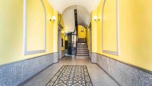 A hallway with a patterned carpet, a staircase, and yellow walls. - JOIVY Cosy 1-Bed Flat In Navigli (Milan)