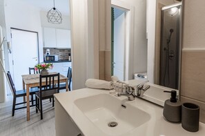 A modern bathroom with a large sink, a shower, and a mirror. - JOIVY Cosy 1-Bed Flat In Navigli (Milan)