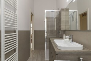 A modern bathroom with a white sink, a large mirror, and a shower enclosure.