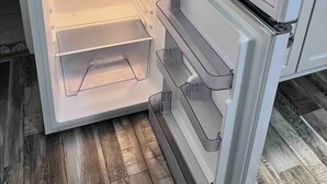 Ett kylskåp med öppna hyllor och ett separat frysfack.