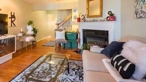 Ein Wohnzimmer mit Sofa, Couchtisch und Kamin. Eine Treppe führt zu einer weiteren Ebene.