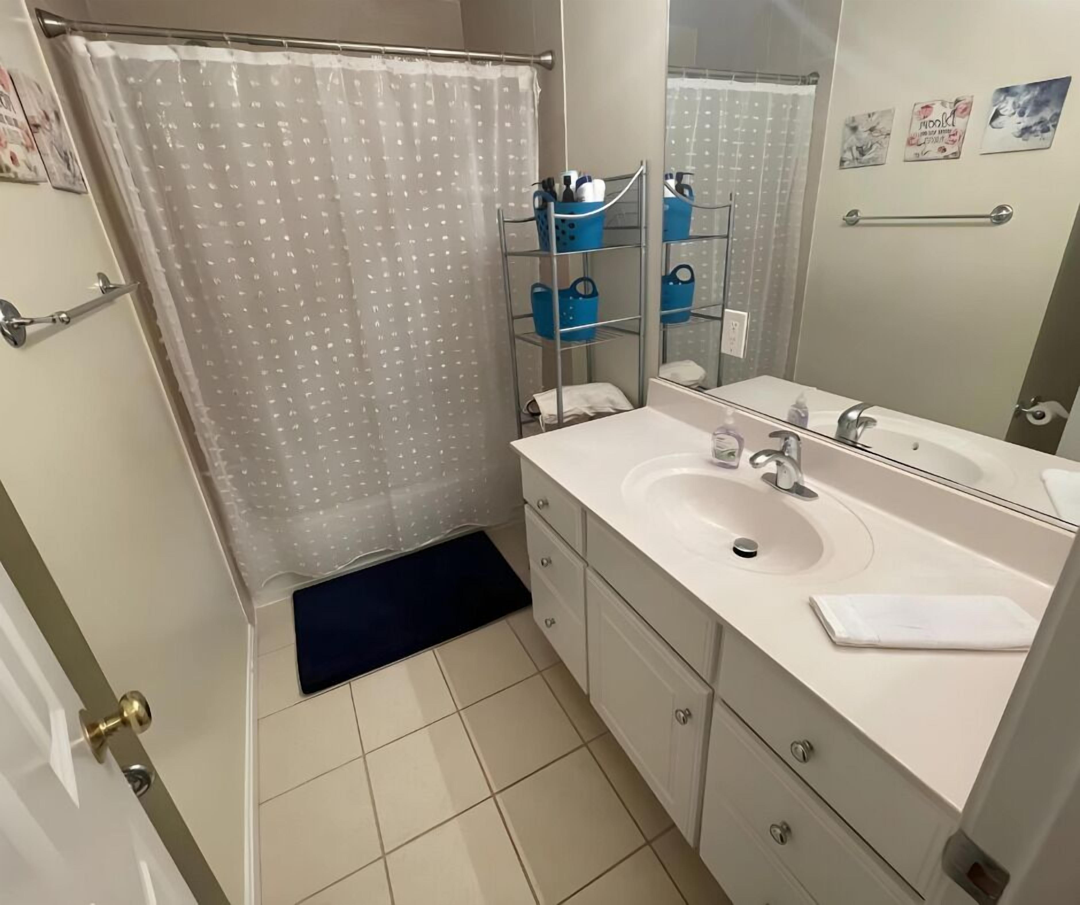 Un baño con lavamanos blanco, espejo y cortina de ducha.