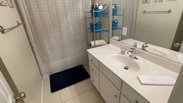 Un baño con lavamanos blanco, espejo y cortina de ducha.