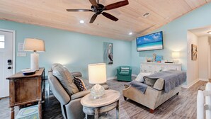 A cozy living room with a ceiling fan, a sofa, a coffee table, and a TV mounted on the wall. - A- Rocks Resort by Silver Sands Vacation Rentals (Port Aransas)
