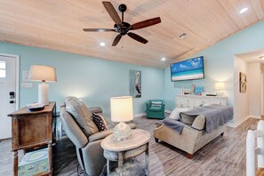 A cozy living room with a ceiling fan, a sofa, a coffee table, and a TV mounted on the wall. - A- Rocks Resort by Silver Sands Vacation Rentals (Port Aransas)