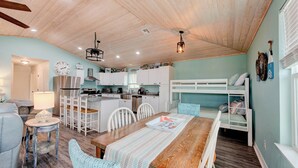 A cozy, well-lit room with a wooden ceiling, a dining table with chairs, a bunk bed, and a kitchenette. - A- Rocks Resort by Silver Sands Vacation Rentals (Port Aransas)