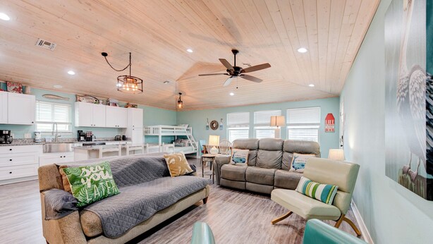 A spacious living area with a wooden ceiling, a sofa, a recliner, and a dining table. - A- Rocks Resort by Silver Sands Vacation Rentals (Port Aransas)