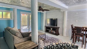 A living room with a sofa, a coffee table, a TV, and a dining area with chairs and a table. - 4 Palms by Silver Sands Vacation Rentals (Port Aransas)