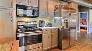 A kitchen with stainless steel appliances, wooden cabinets, and a visible fire safety sign. - 4 Palms by Silver Sands Vacation Rentals (Port Aransas)