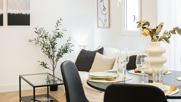 Un espace repas moderne avec une table ronde, des chaises noires et un luminaire suspendu.