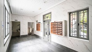 Un couloir aux murs de marbre, un escalier et une rangée de casiers.
