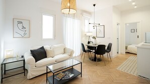 Un salon moderne avec un canapé blanc, une table basse en verre et un coin repas comprenant une table et des chaises.