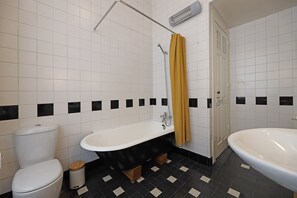 Een badkamer met een wit toilet, een zwart bad en een witte wastafel.