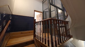 Eine Holztreppe mit Glastrennwand, die zu einer Zwischenebene führt.
