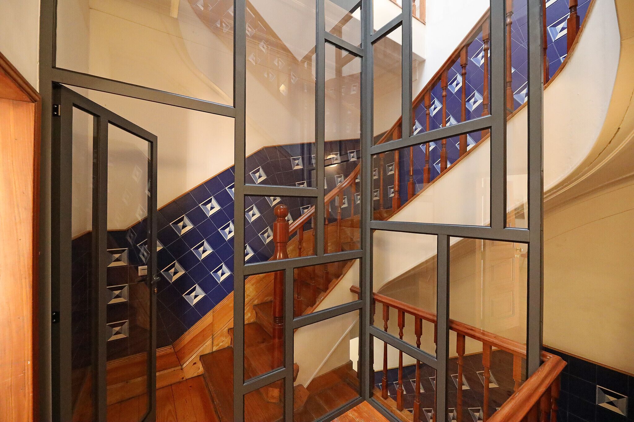 A staircase with a wooden handrail and a blue patterned carpet.
