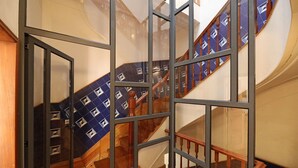 Una scala con ringhiera in legno e tappeto azzurro a motivi decorativi.
