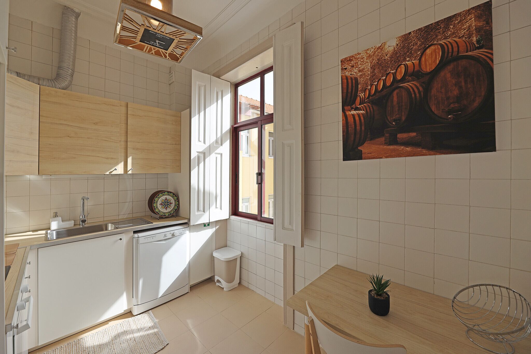 A modern kitchen with white cabinetry, a dishwasher, and a window with a view of wine barrels.