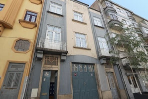 A multi-story building with a mix of architectural styles, including a prominent blue door and a balcony with a metal railing.