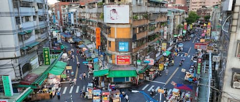 A bustling urban street scene with multi-story buildings, shops, and pedestrians.
