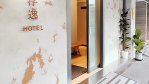 A hotel entrance with a modern design, featuring a glass door and a visible interior with a wooden bench. - FooYee Hotel-YongHe (New Taipei City)