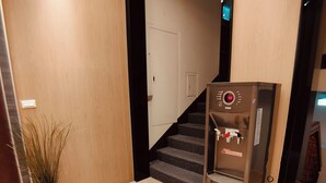 A hallway with a refrigerator, a potted plant, and a staircase. - FooYee Hotel-YongHe (New Taipei City)