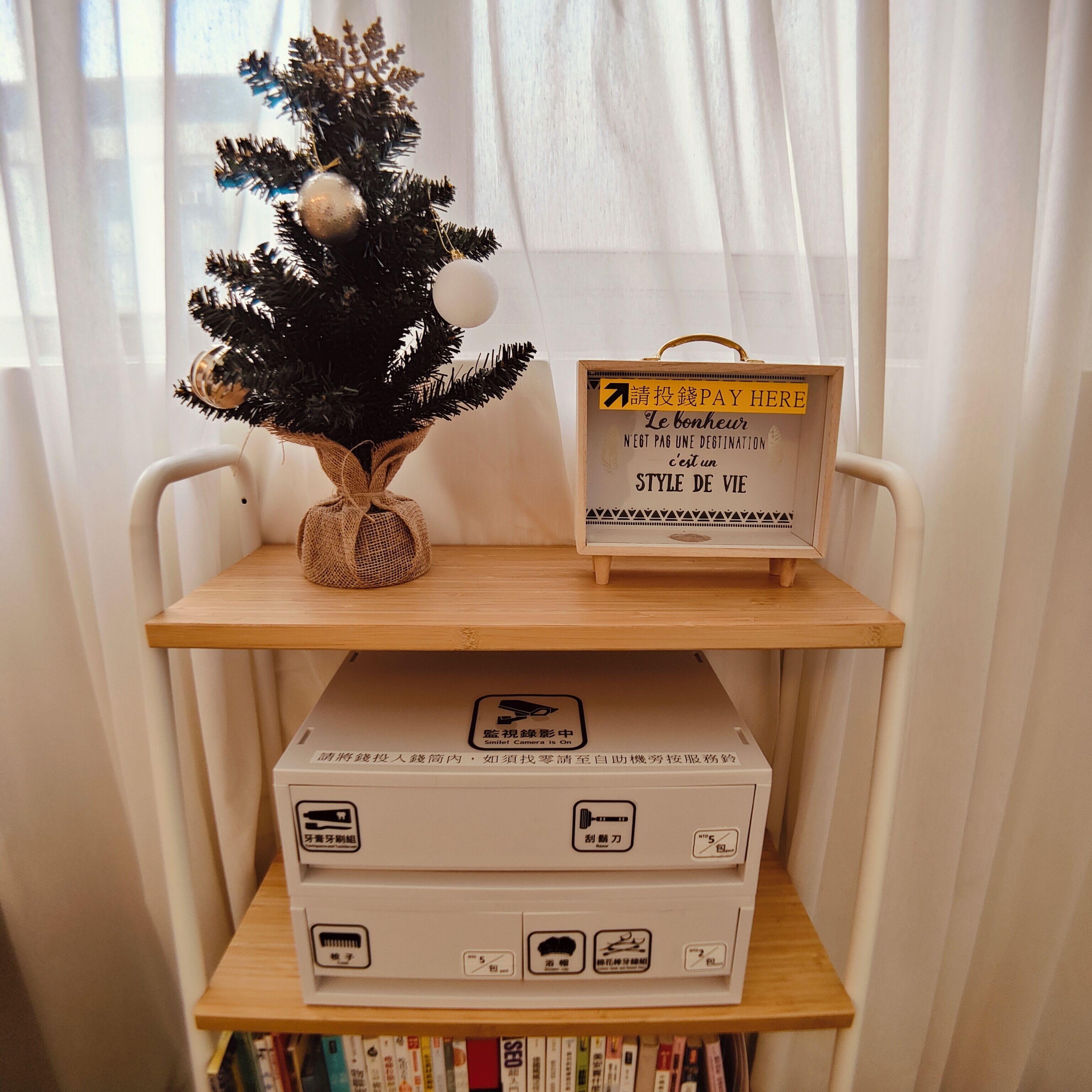 A small Christmas tree on a shelf, a sign with text, and a box with various symbols.