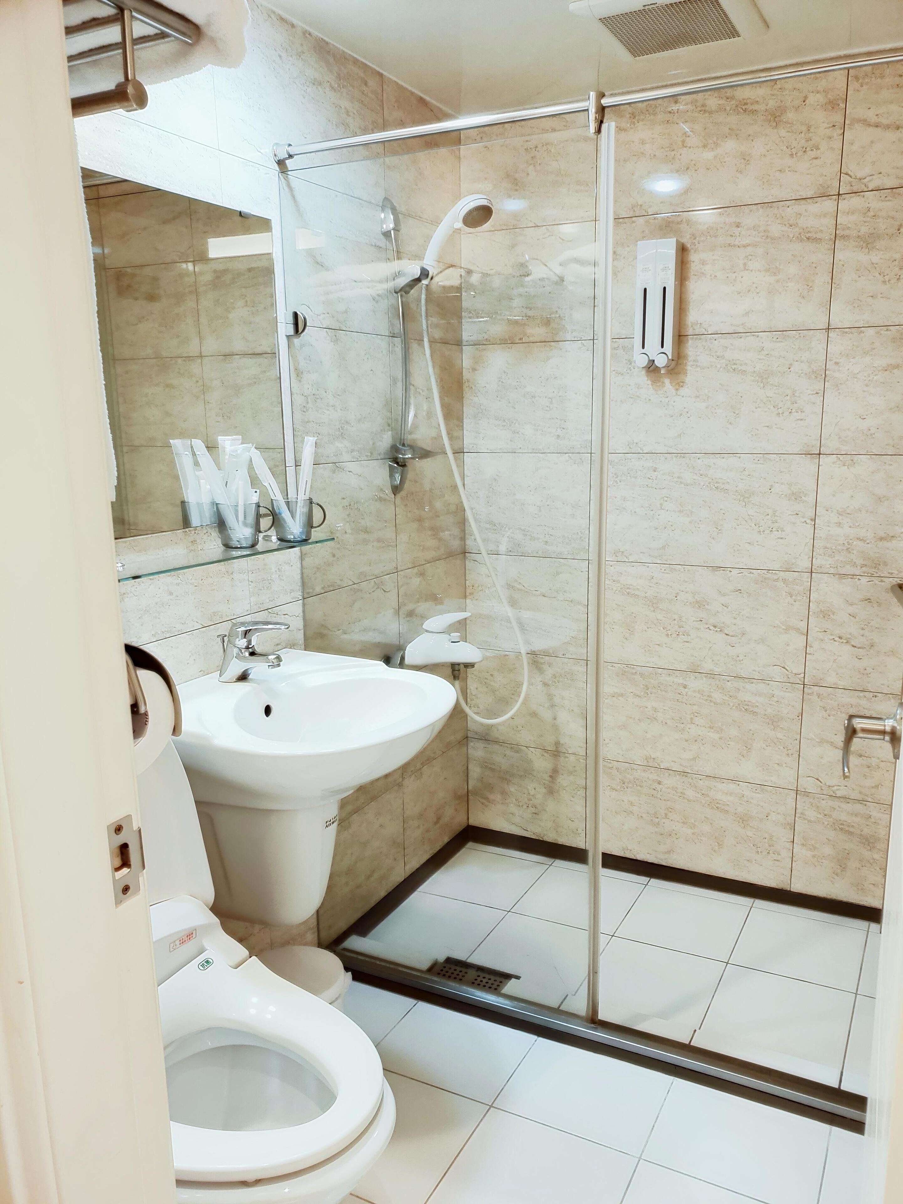 A modern bathroom with a glass-enclosed shower, a white sink, and a toilet.