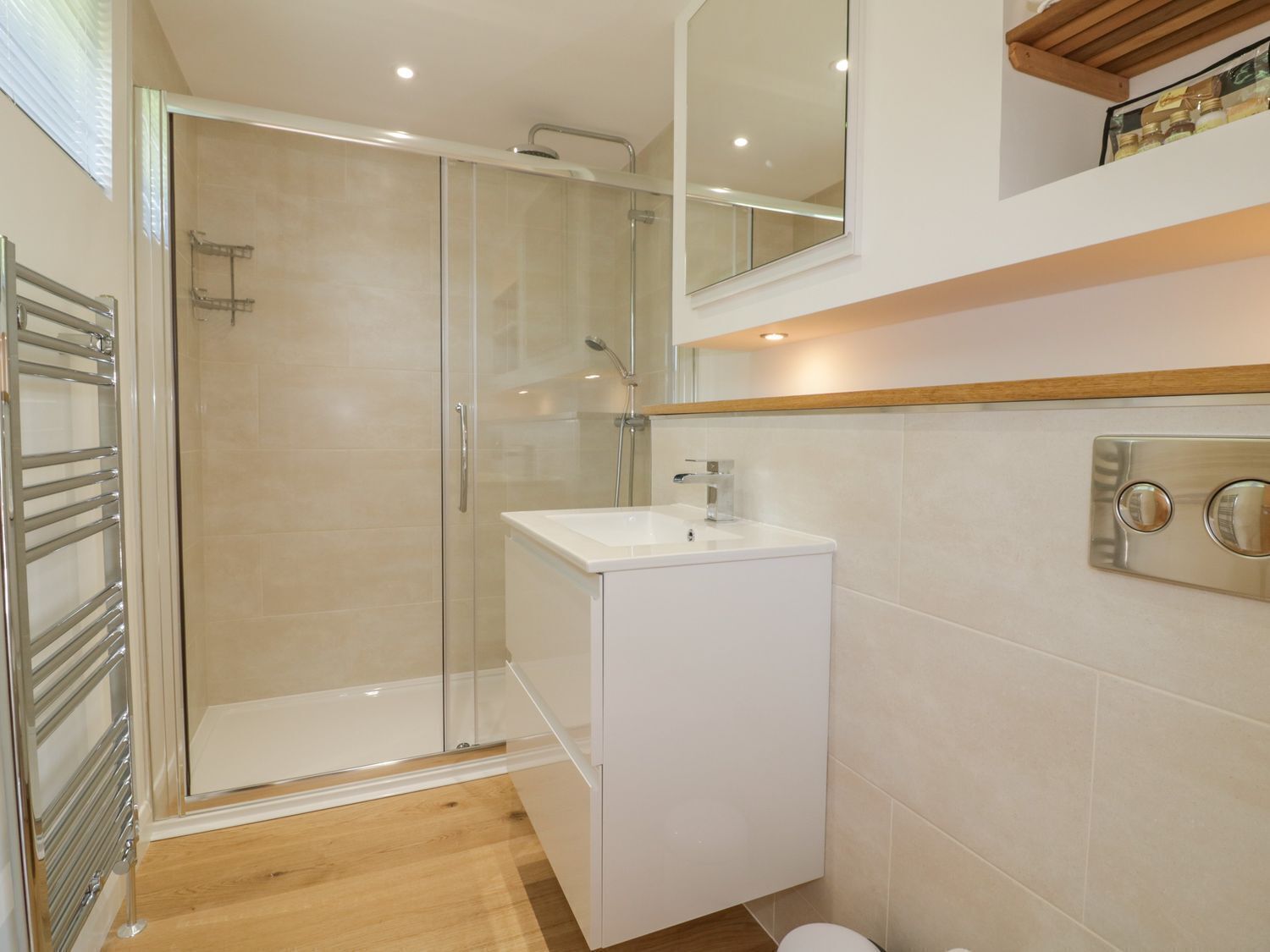 Un baño moderno con ducha de vidrio, un lavabo blanco y un inodoro.