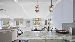 A spacious kitchen with a large island, pendant lights, and a view of the outdoors. - FrippLife, Walk to Beach, Golf Cart Included - 707 Bluefish (Fripp Island)