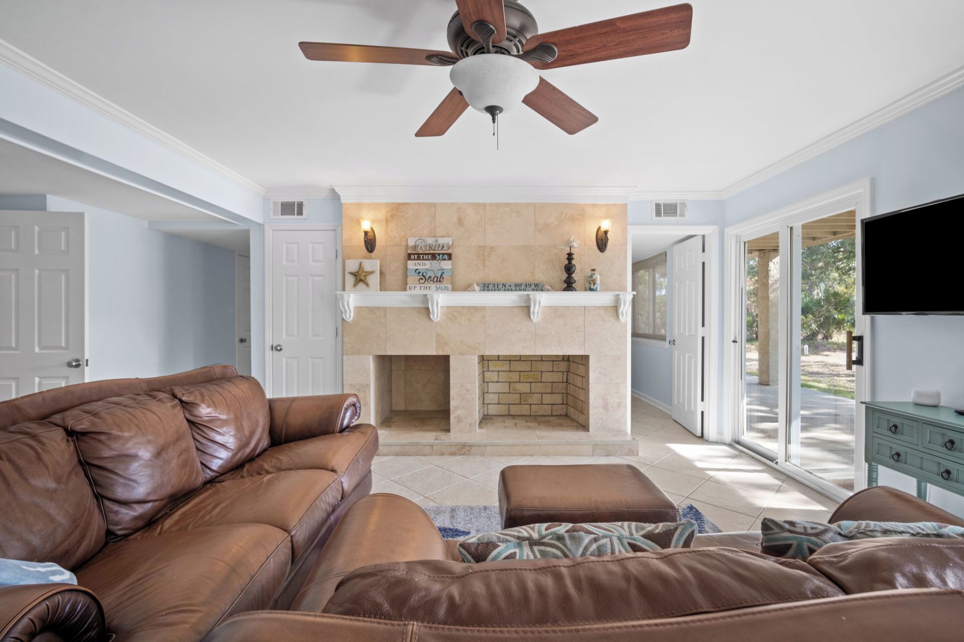A spacious living room with a leather sofa, a fireplace, and a television.