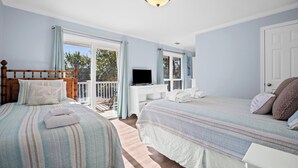 A bedroom with two beds, a TV, and a balcony. - FrippLife, Walk to Beach, Golf Cart Included - 707 Bluefish (Fripp Island)