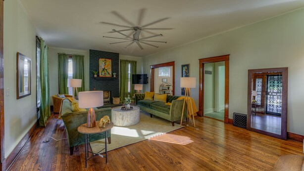 A spacious living room with hardwood flooring, a green sofa, a round coffee table, and a ceiling fan. - Funky Memphis Game House! FirePit, Gtd pkg, Games! (Memphis)