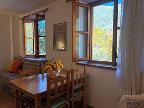 A cozy room with a wooden table, a bench, and a window with a view of trees. - Small studio apartment - Cuc 7 (Pla de l'Ermita)