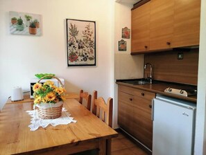 Enjoy cooking in this cozy kitchen with a table, chairs, refrigerator, sink, and kettle.