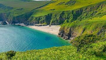 A coastal landscape with a beach, cliffs, and a clear view of the sea.