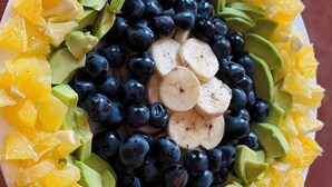 Ensalada de frutas con piña, arándanos y rodajas de plátano sobre un plato blanco.