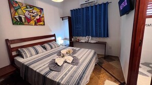 A bedroom with a bed, a painting, an air conditioner, a TV, and a window with curtains. - Residencial Bem te vi (Jijoca de Jericoacoara)