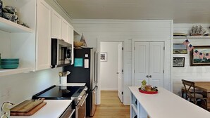 Uma cozinha moderna com armários brancos, eletrodomésticos de aço inoxidável e piso de madeira.