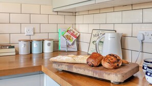Una encimera de cocina con un pan, dos pasteles, un libro de cocina y una cafetera.