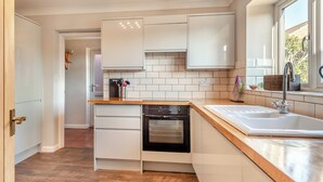 Una cocina moderna con armarios blancos, encimera de madera, horno empotrado y ventana con vistas a zonas verdes.