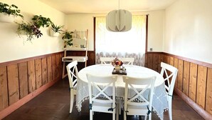 A dining area with a round table, white chairs, a wooden bench, and potted plants on the wall. - Mendocino Coast Home with Sauna and Fireplace  (Fort Bragg)