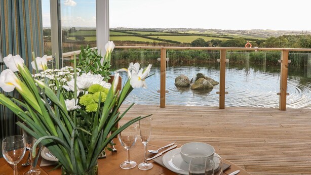 A dining table with a view of a lake and countryside. - 14 Faraway Fields (Liskeard)