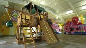 A wooden play structure with a slide and climbing area, surrounded by colorful inflatable decorations. - CONDO MARINA G  BY TRVL2HM (Nuevo Nayarit)