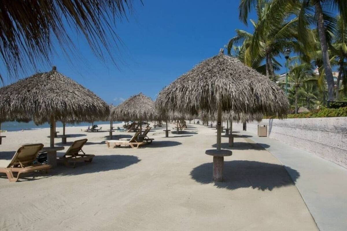 A beachside resort with thatched umbrellas, sun loungers, and a clear view of the ocean.