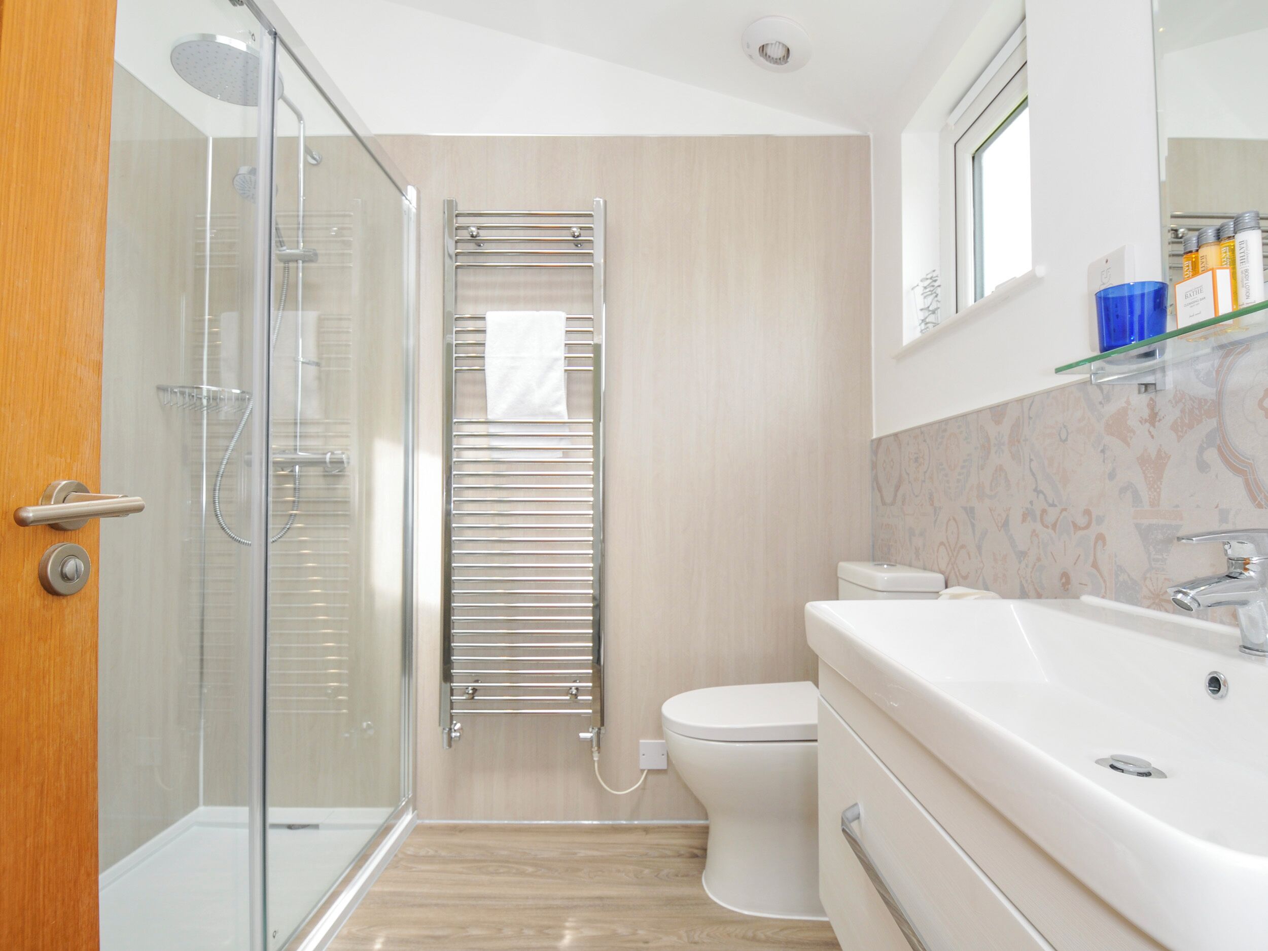 A modern bathroom with a glass shower enclosure, a white toilet, and a vanity with a mirror.