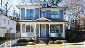 A two-story house with a front porch, a small attached garage, and a fenced yard.